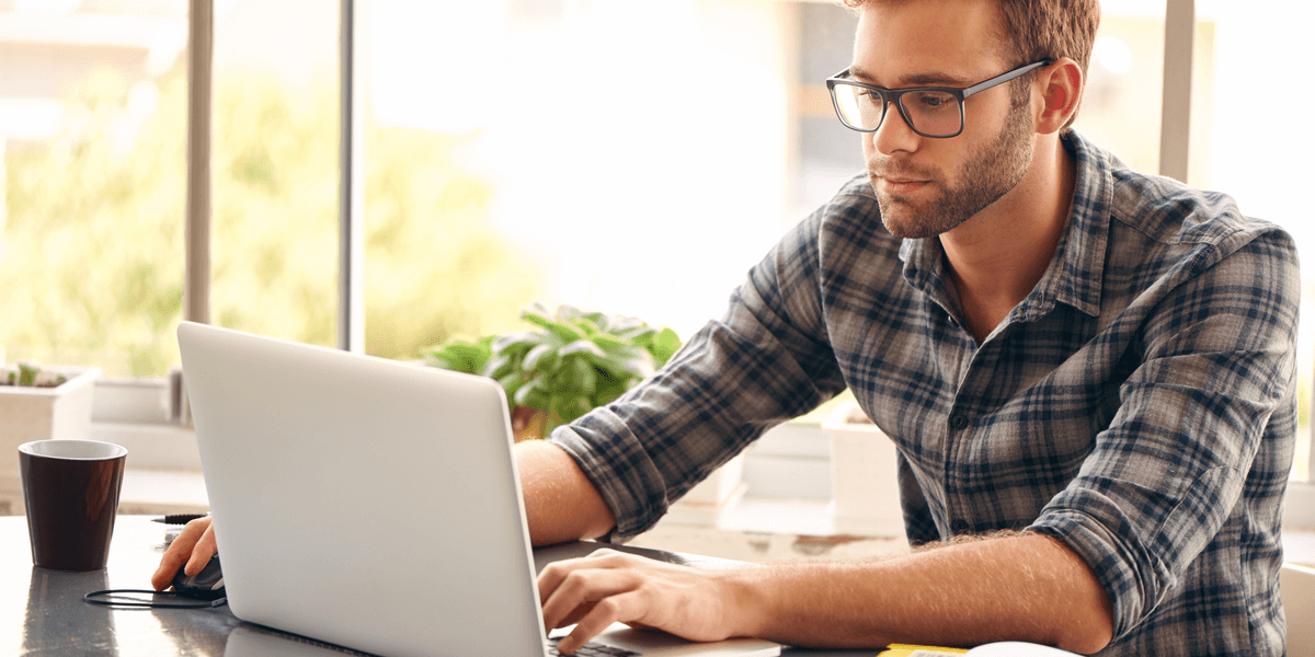 Ein junger Mann mit Brille arbeitet an seinem Laptop